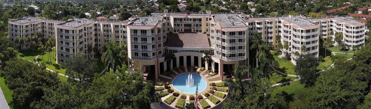 Aerial view of a building complex with a central fountain and landscaped surroundings.