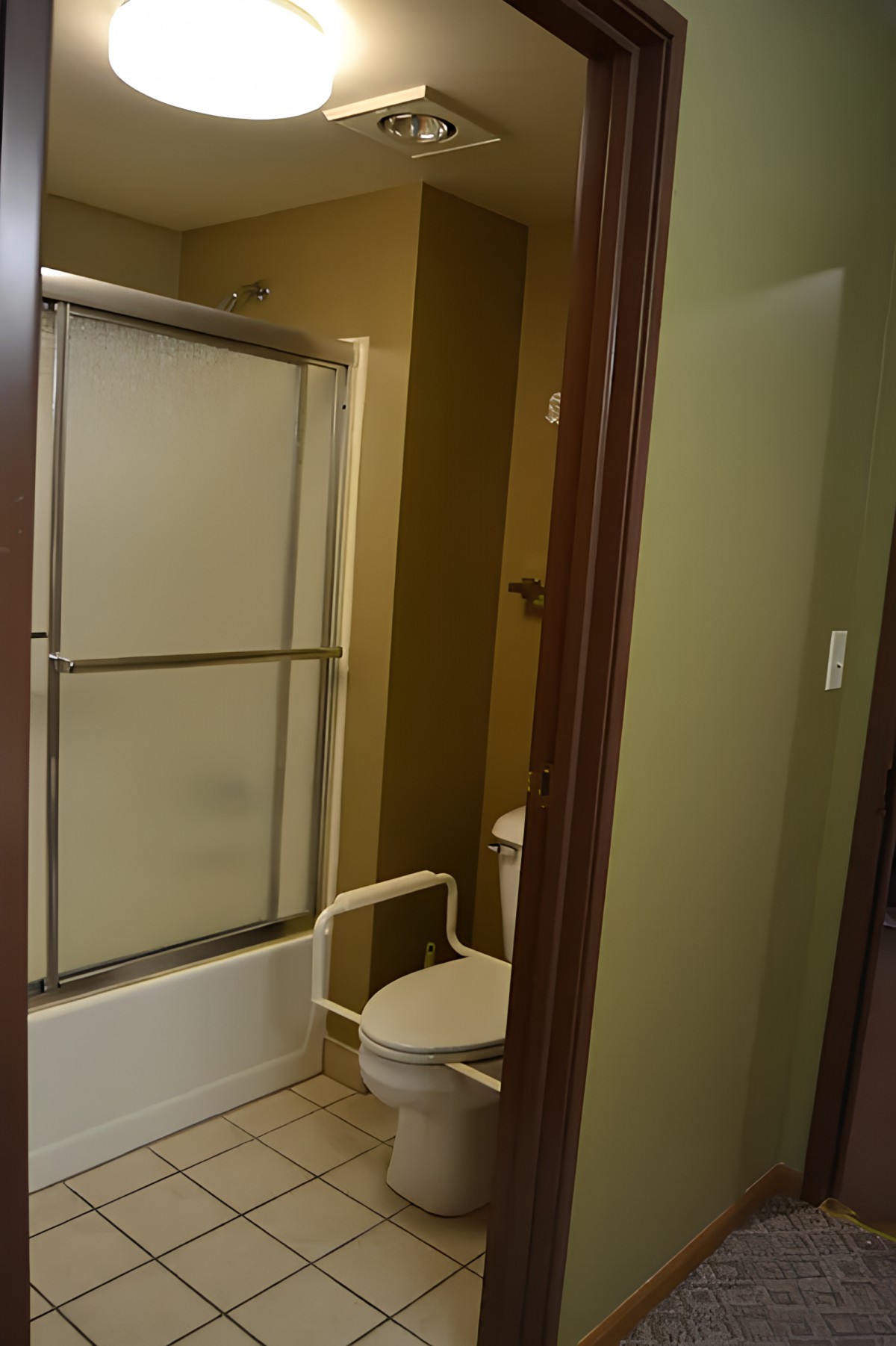 A bathroom with a shower and toilet featuring sliding glass doors.