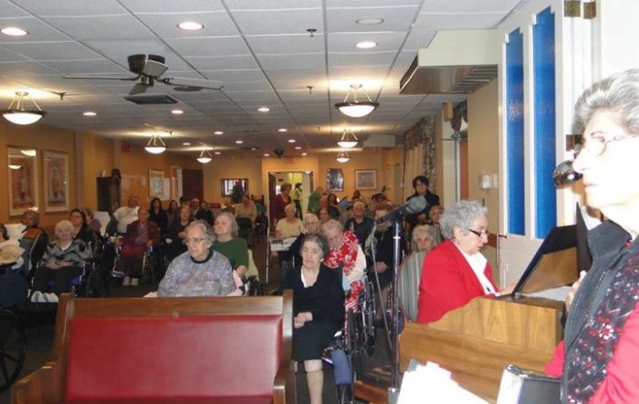 A community gathering with an audience listening to a speaker indoors.
