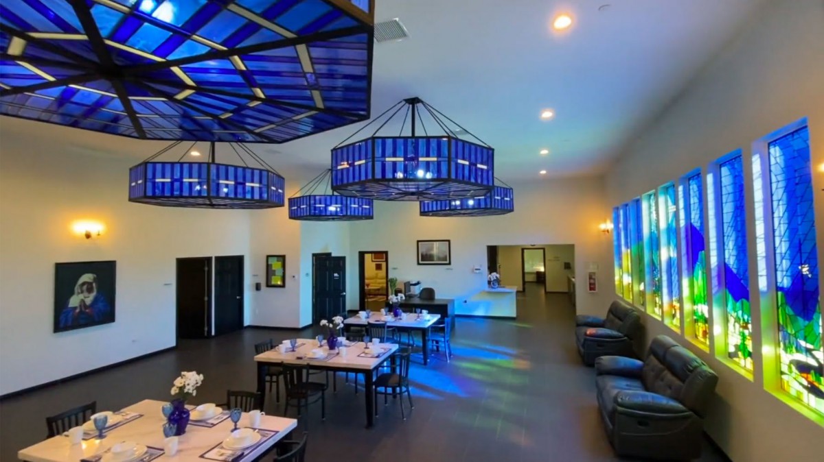 A modern dining area with blue-lit chandeliers casting colorful reflections on the floor.