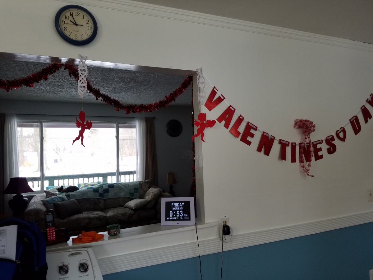 A cozy living space decorated for Valentine's Day with a festive banner and red accents.