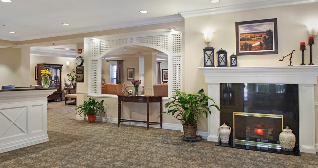 A cozy lobby area featuring a fireplace, decorative plants, and elegant furniture.