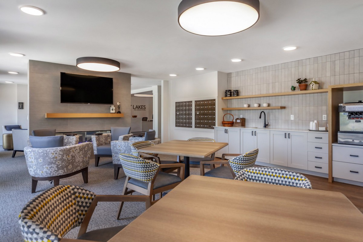 A modern living room with a seating area, kitchenette, and contemporary lighting.