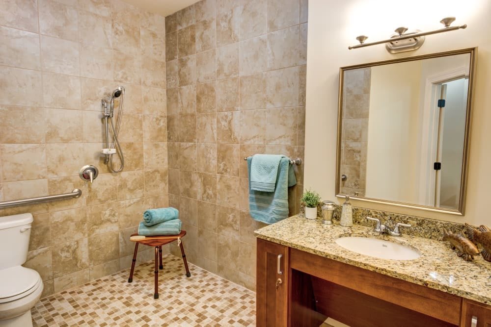 A modern bathroom with a spacious walk-in shower and a granite vanity.