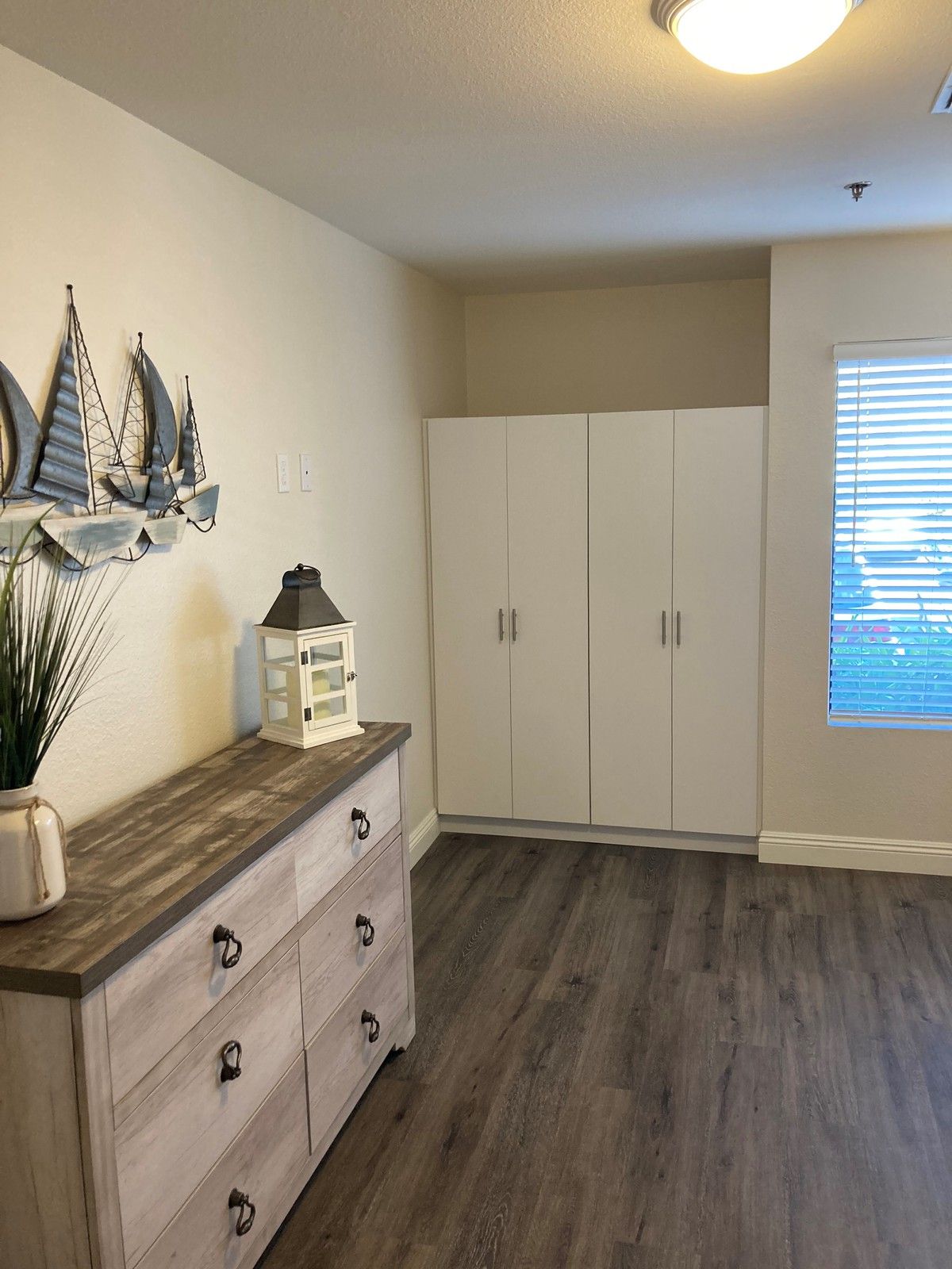 A cozy bedroom featuring a dresser and wardrobe with nautical decor.