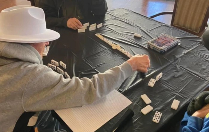 Two people playing a game of dominoes at a table.