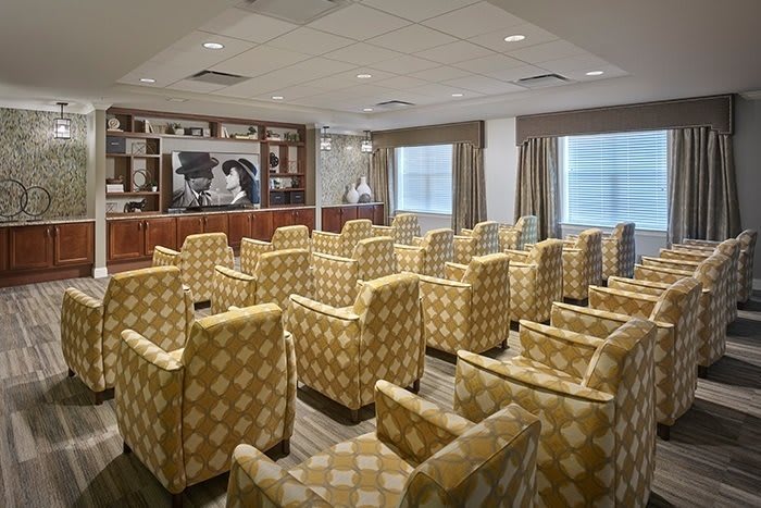 A conference room with theater-style seating and a large projector screen at the front.