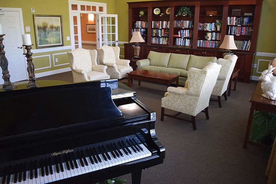 A cozy living room with a grand piano, comfortable seating, and a bookshelf.