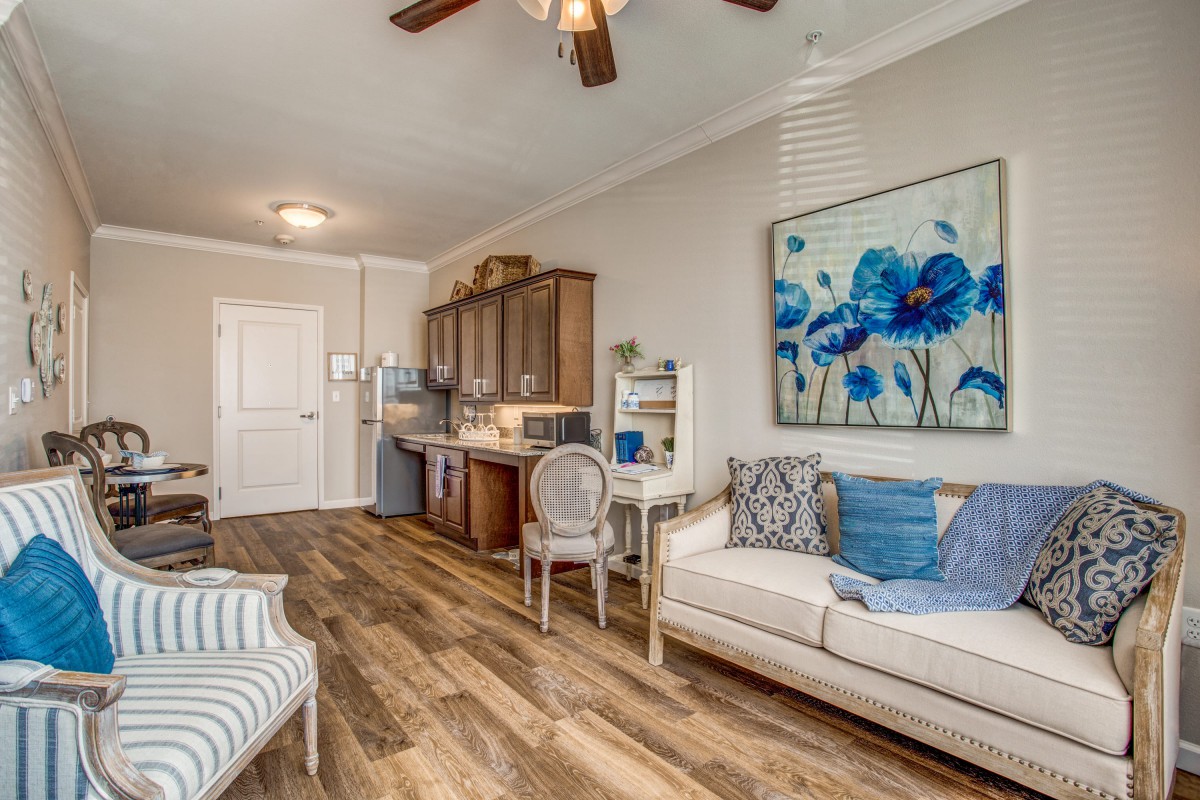 A cozy living area with a sofa, kitchenette, and vibrant artwork.