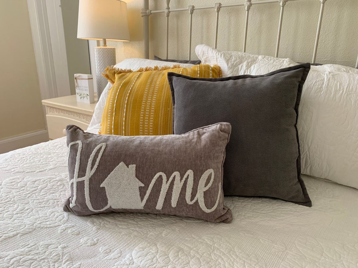 A welcoming display of decorative pillows on a bed, including one with the word 'Home'.