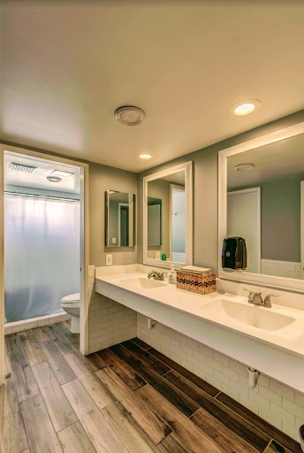 A sleek and modern bathroom featuring a dual vanity, large mirrors, and a shower enclosure.