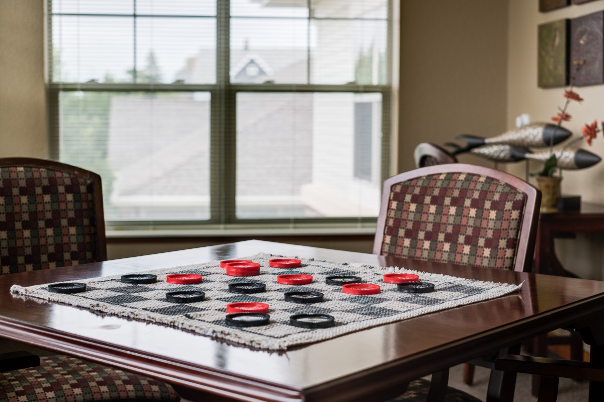 A checkers game set up on a table by the window.