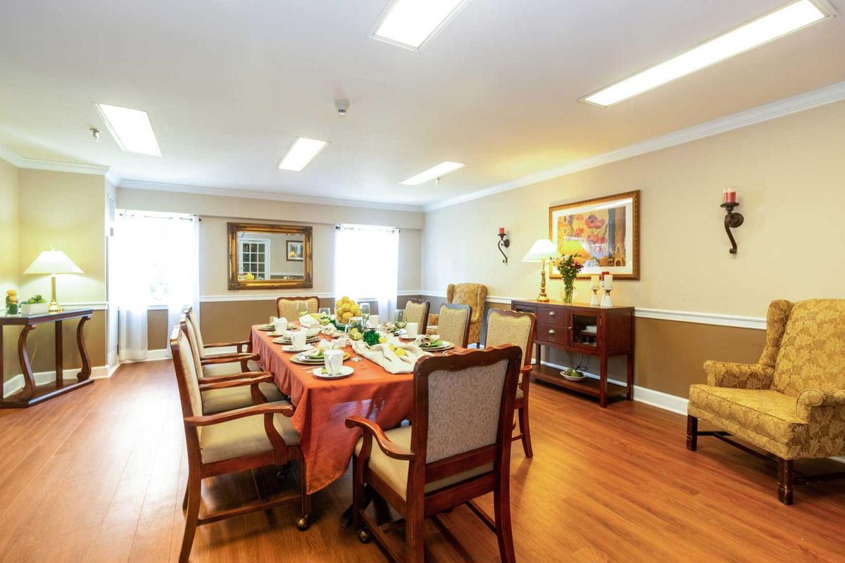 A well-decorated dining room featuring a long table set for a meal, surrounded by chairs and enhanced with artwork on the walls.