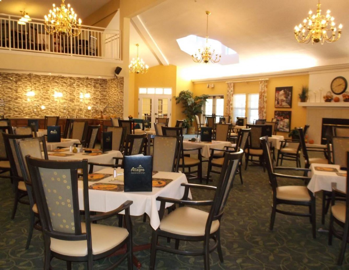 An elegant restaurant dining room with chandeliers and neatly arranged tables and chairs.