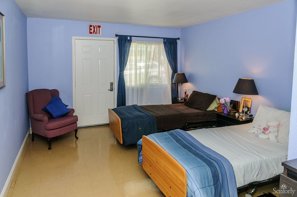 A cozy bedroom with two beds, blue walls, and a small seating area.