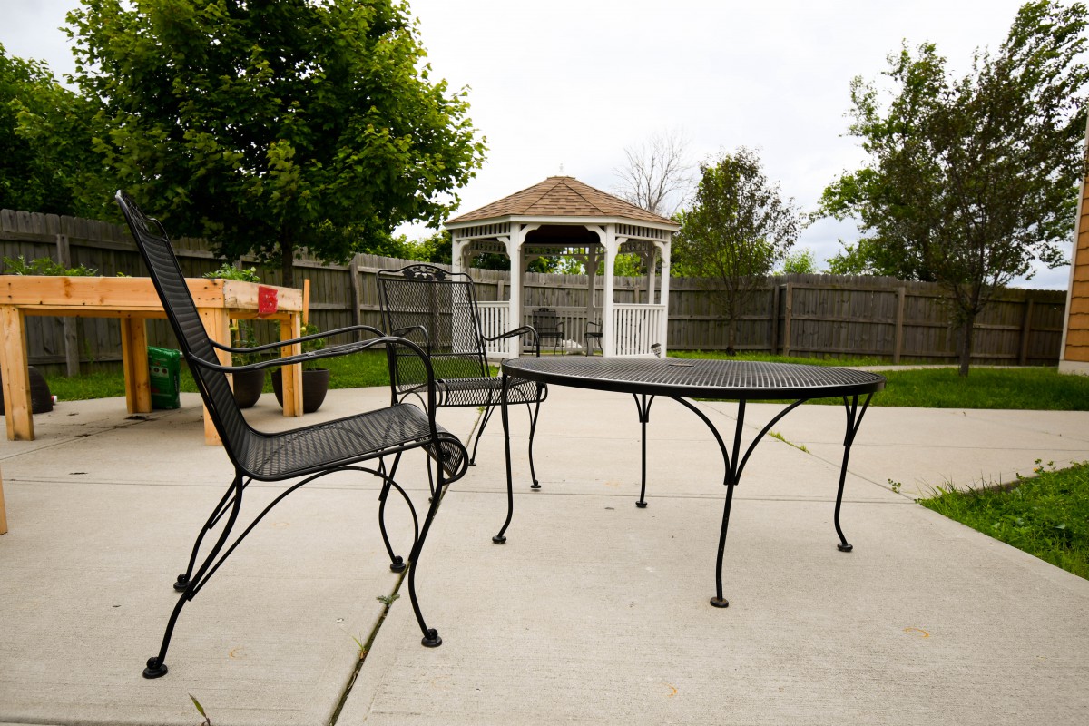 A backyard patio with metal furniture and a gazebo in the background.