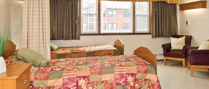 A bedroom with two twin beds, floral bedding, and a large window with curtains.