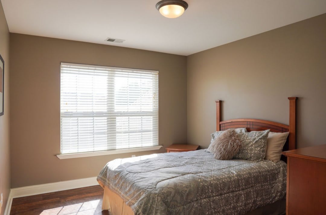 A minimalist bedroom with natural light streaming through a large window.