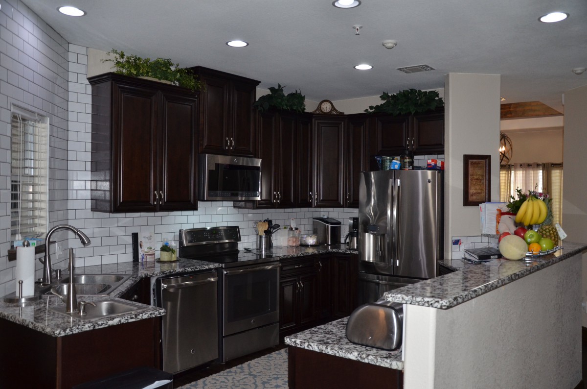 A modern kitchen with dark cabinets and stainless steel appliances.