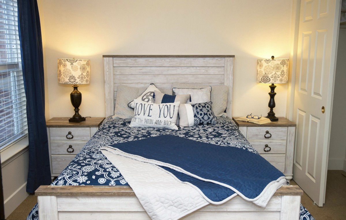 A cozy bedroom with a neatly made bed, complemented by decorative pillows and flanked by two lamps on nightstands.