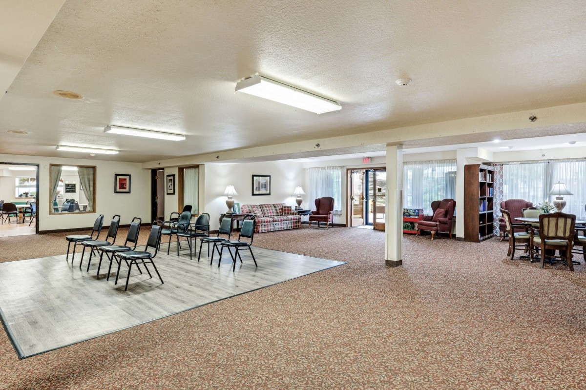 A spacious and well-lit meeting room with chairs arranged in rows, a seating area with sofas, and large windows.