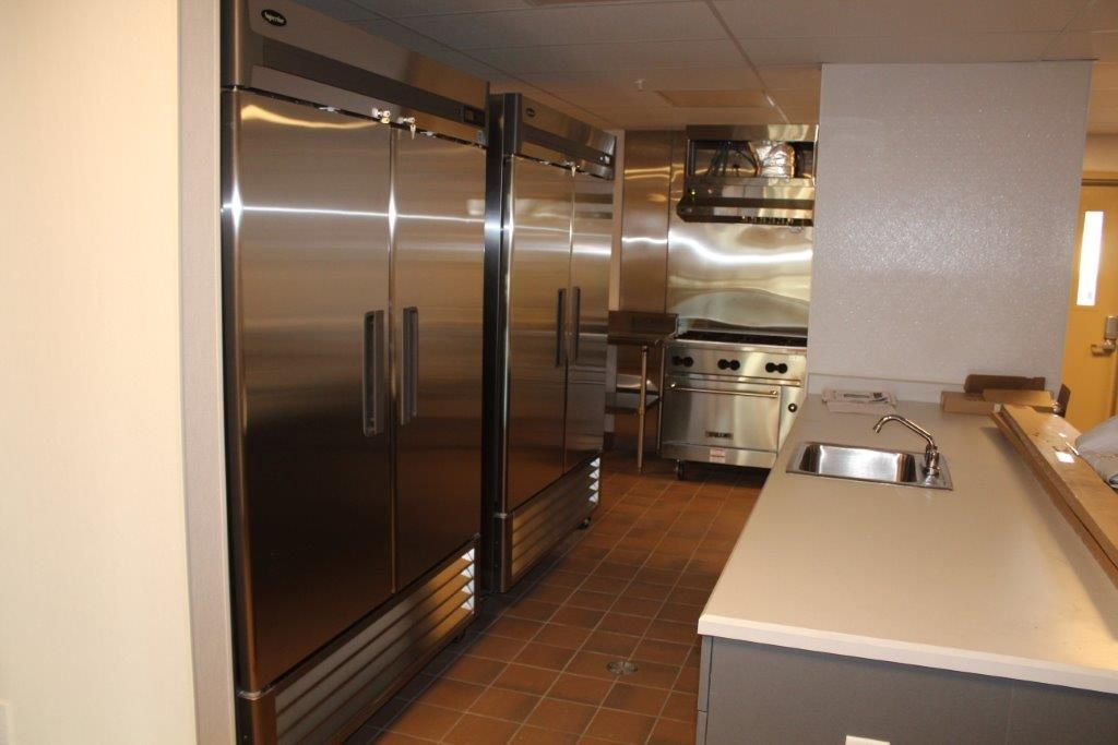 A commercial kitchen featuring stainless steel appliances, including refrigerators and cooking equipment.