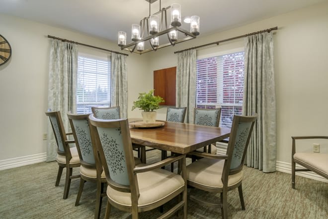 A well-appointed dining room featuring a large wooden table, upholstered chairs, and an elegant chandelier.