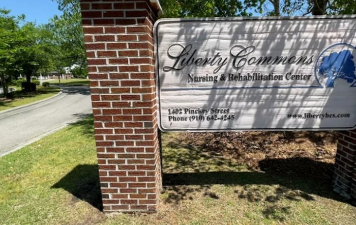 A sign for Liberty Community Nursing & Rehabilitation Center, mounted on a brick column.