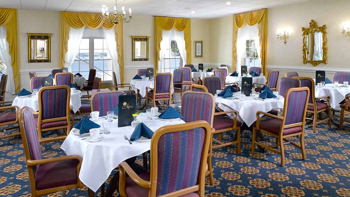 An elegant dining room with neatly arranged tables and chairs, set for a meal.