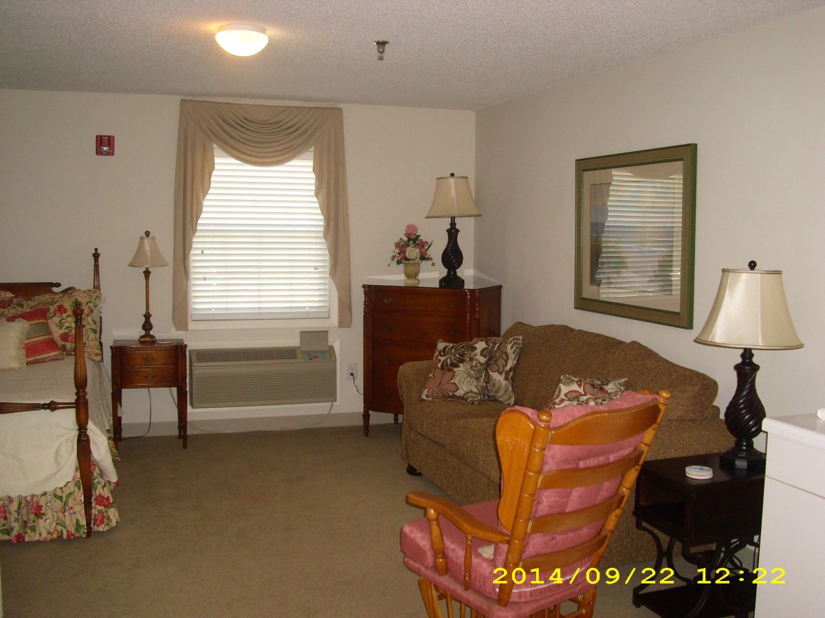A cozy living room with a sofa, chairs, lamps, and a window with curtains.