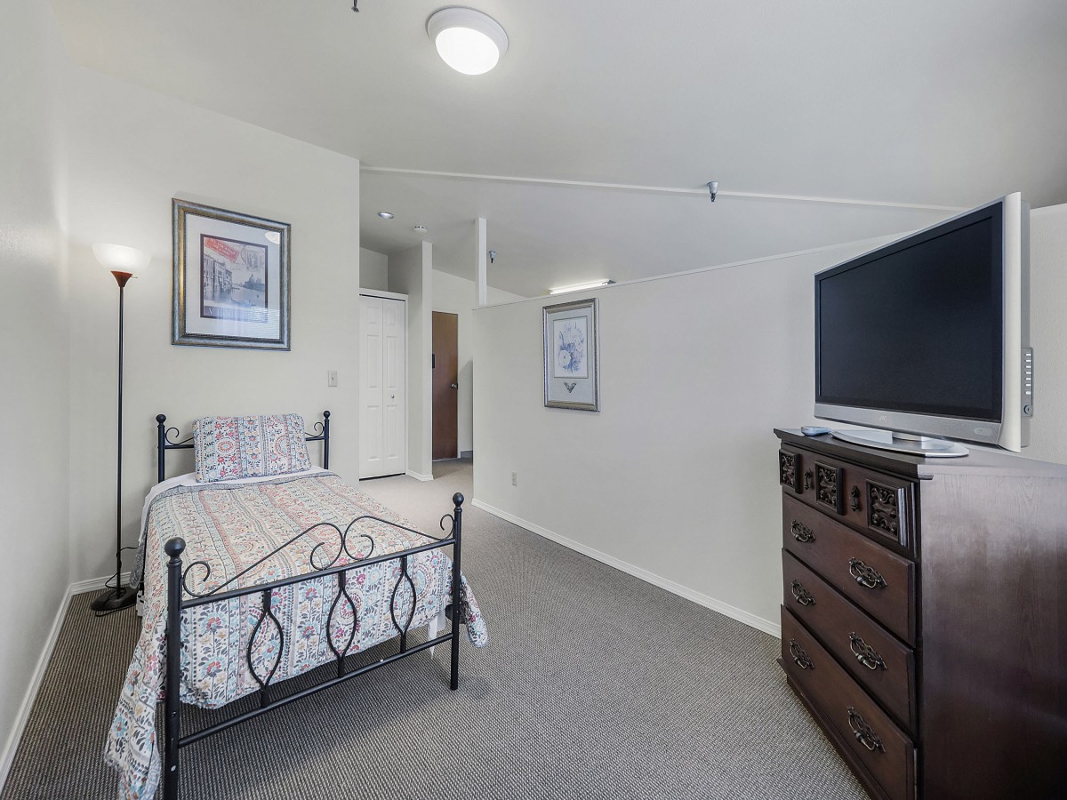 A cozy bedroom with a single bed, dresser, and television.