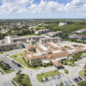 Aerial view of a large building complex with surrounding parking lots and greenery.