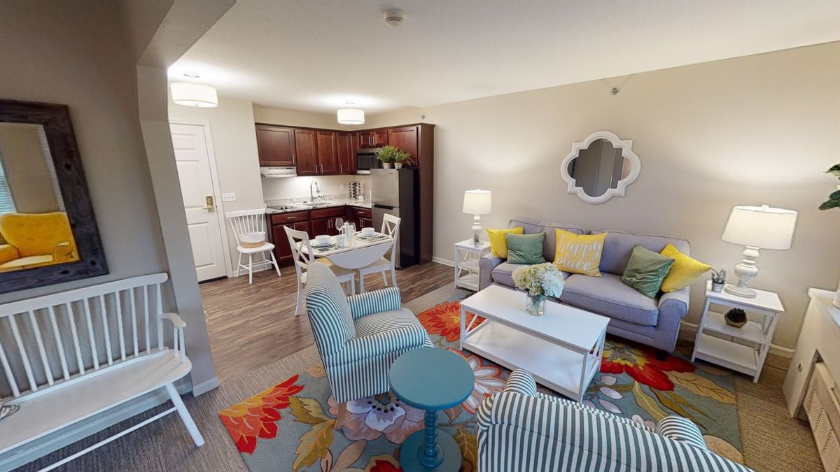 A modern apartment with a vibrant living room and kitchen area, featuring colorful furniture and decor.