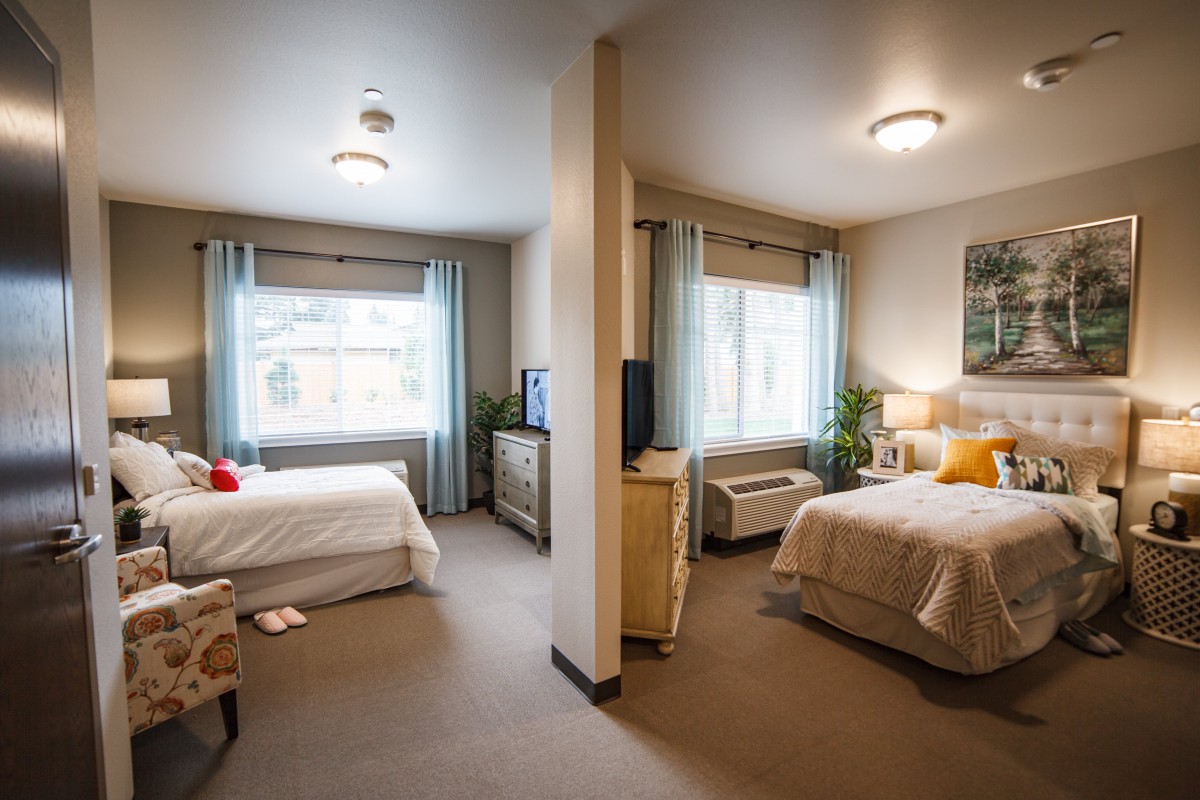 A cozy hotel double room with two separate beds, featuring light decor and ample natural lighting.