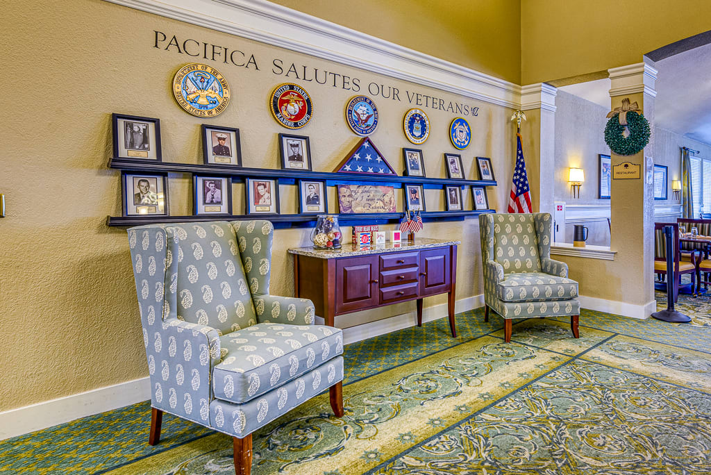 A decorated interior space featuring military memorabilia and portraits, with two chairs and flags displayed.