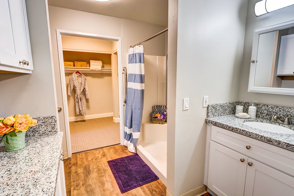 A modern bathroom with a striped shower curtain and an adjacent walk-in closet.