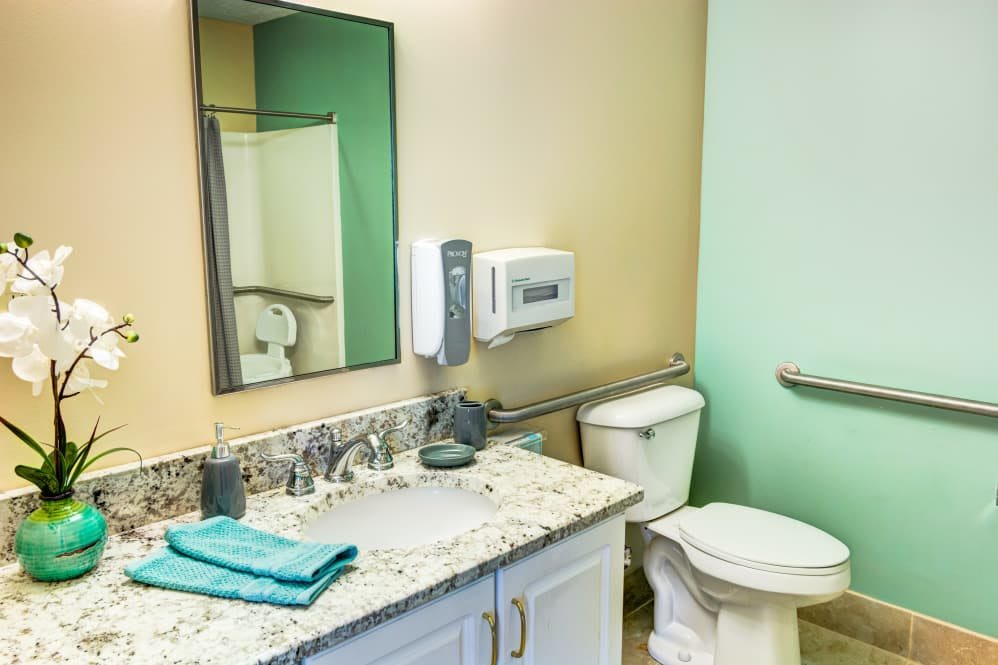 A clean and organized bathroom with a sink, mirror, and toilet.
