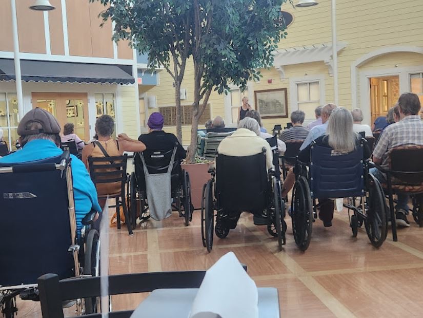 A group of elderly people in wheelchairs gathered indoors.