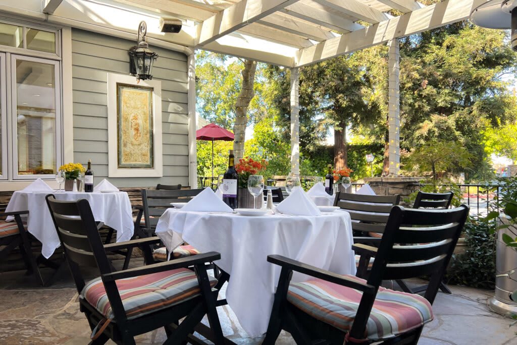 A cozy outdoor dining area with elegantly set tables on a covered patio.
