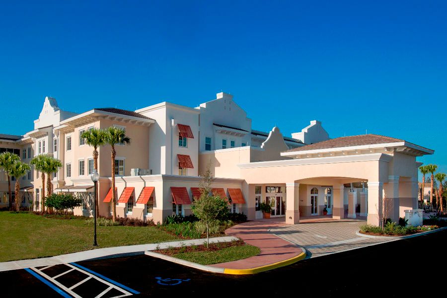 A modern hospital building with a clear blue sky in the background.