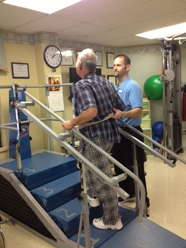 A physical therapist assisting an elderly patient in a rehabilitation setting, focusing on stair climbing.