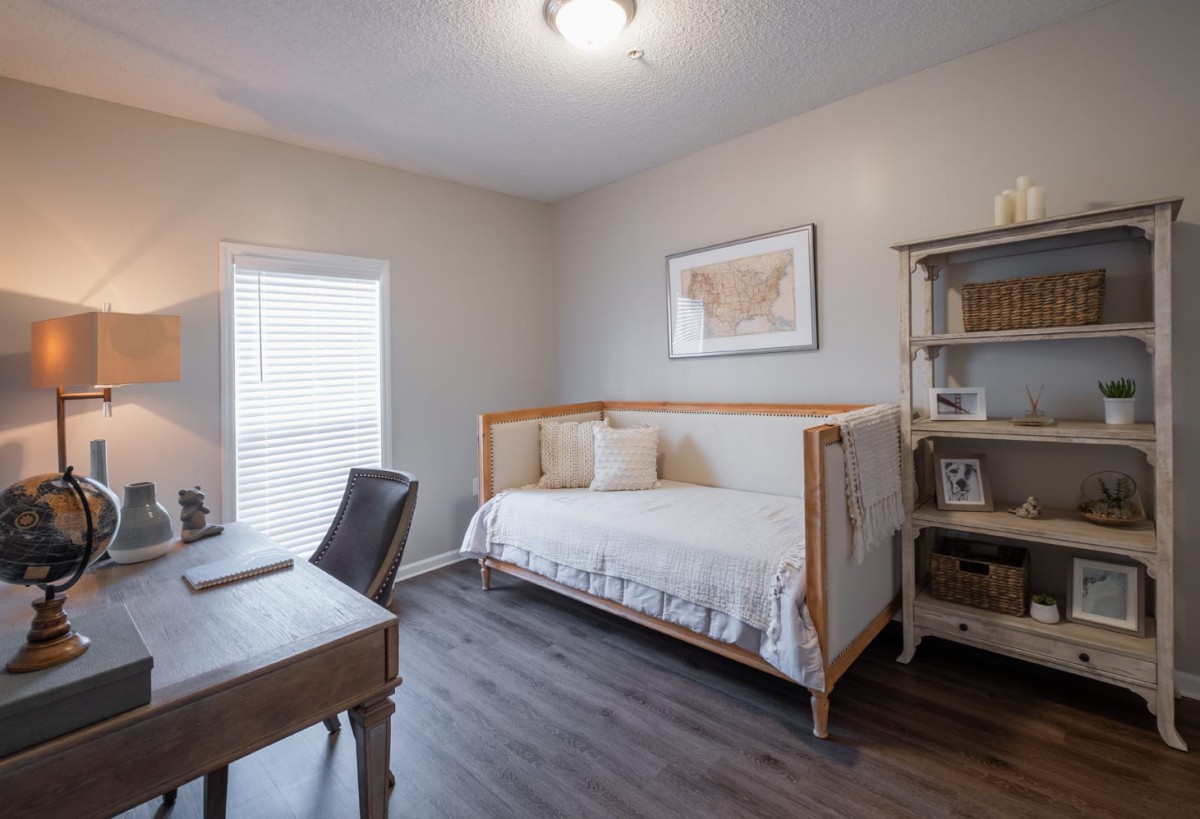 A cozy room with a daybed, desk, and bookshelf, perfect for a tranquil home office setup.