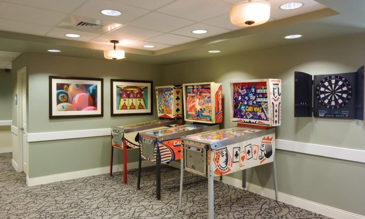 A cozy room featuring three vintage pinball machines with colorful artwork, perfect for an arcade gaming experience.