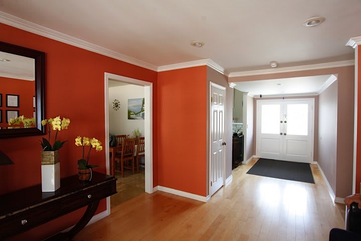 A welcoming home entrance with a red accent wall and wood flooring.