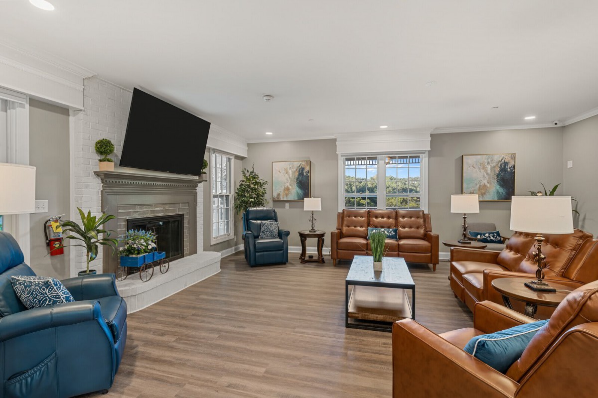 A modern living room with comfortable seating and a large television above the fireplace.