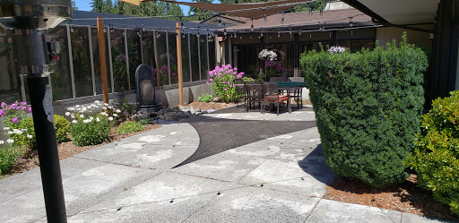 A serene outdoor patio space surrounded by lush greenery and blooming flowers, perfect for relaxation.