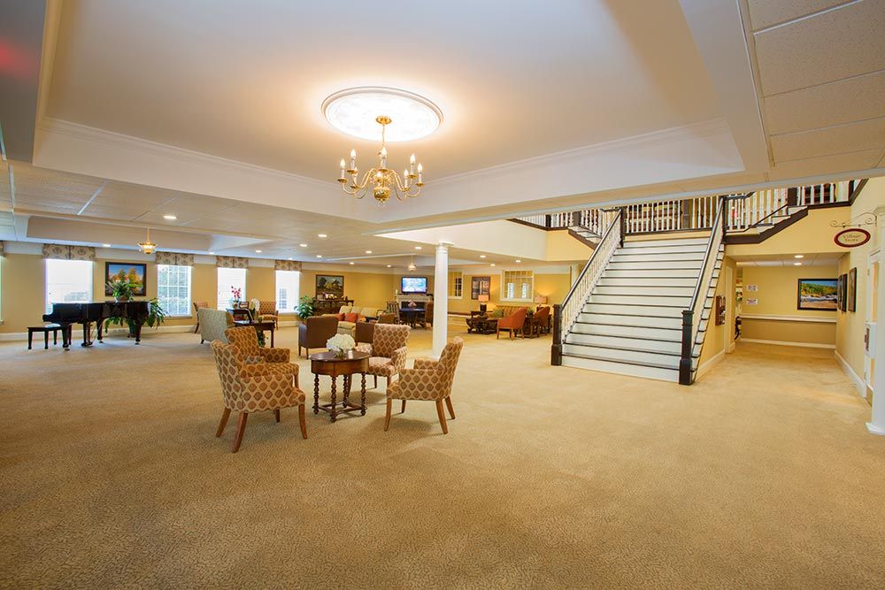 A spacious lobby with a chandelier, seating area, and ascending staircase.