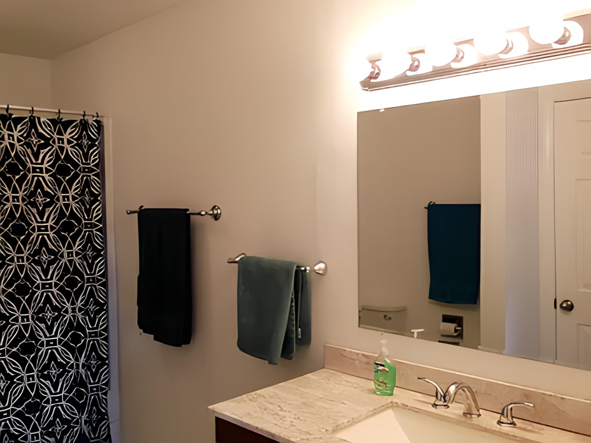 A modern bathroom with a large mirror above the sink and neatly hung towels.