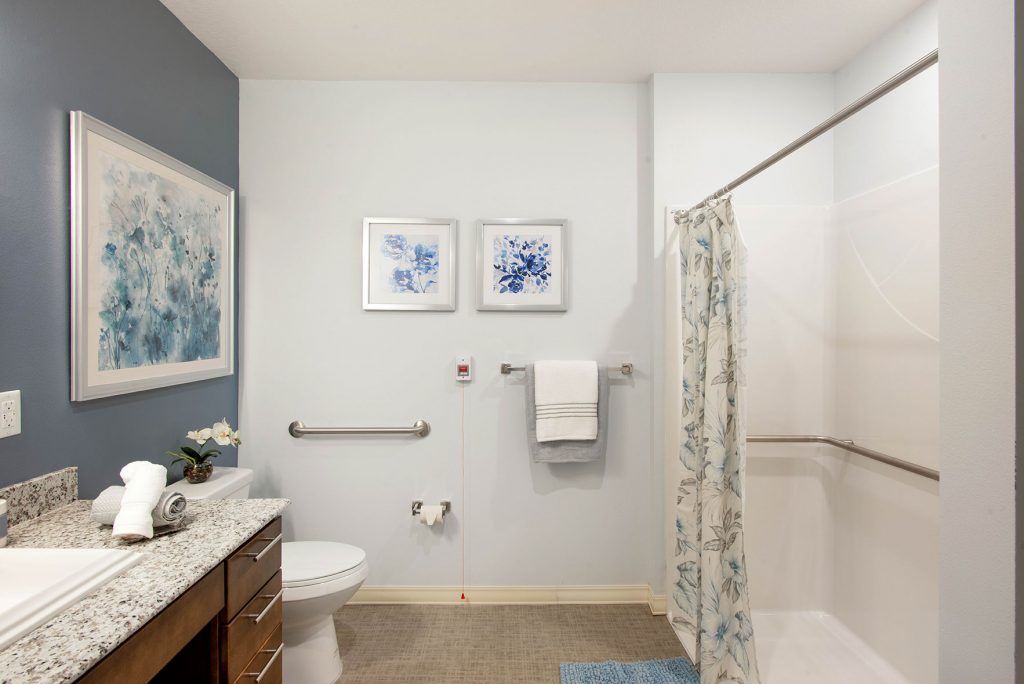 A modern bathroom with a shower, artwork, and neatly arranged towels.
