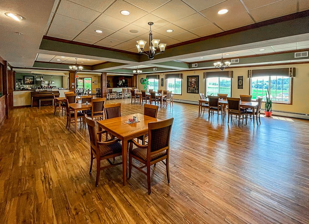 Spacious dining room with wooden floors and neatly arranged tables and chairs.